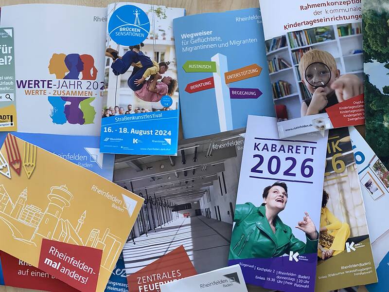 Verschiedene Flyer und Broschüren sind auf einem Tisch verteilt. 