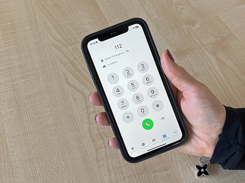 Eine weibliche Hand hält ein Smartphone, auf dem die Notrufnummer 112 gewählt ist. 