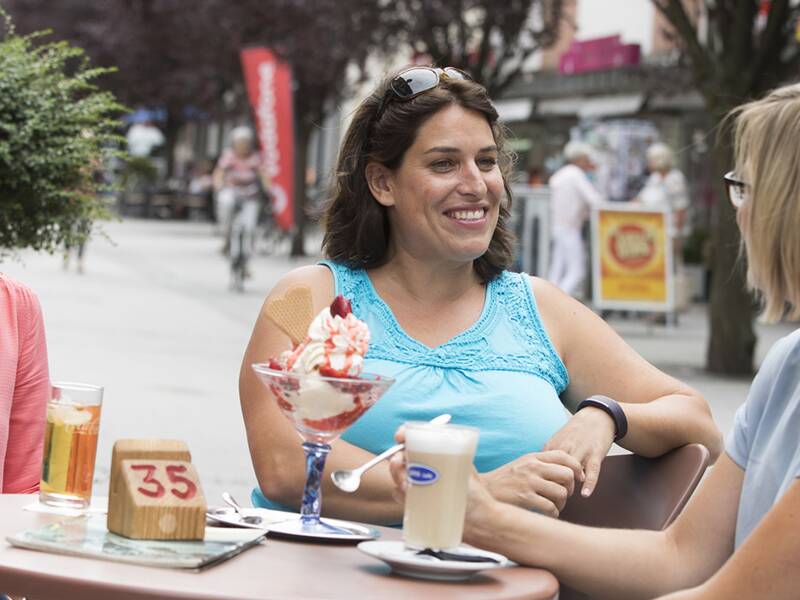 Drei Frauen essen an einem Tisch Eis und unterhalten sich.