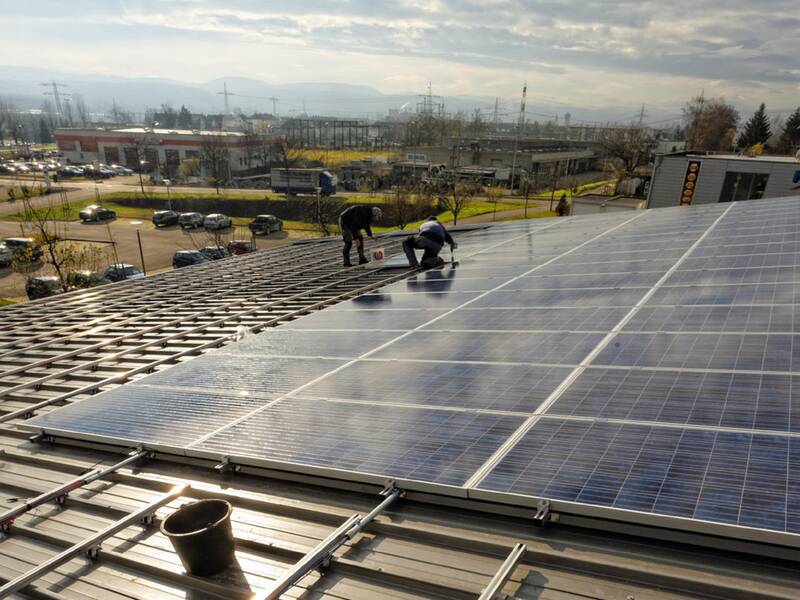 Zwei Arbeiter installieren eine Photovoltaik-Anlage auf einem Dach