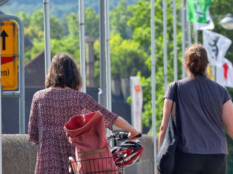 Auf der Rheinbrücke gehen ein paar Fußgänger,, Im vordergrund das Grenzschild zwischen Schweiz und Deutschland 