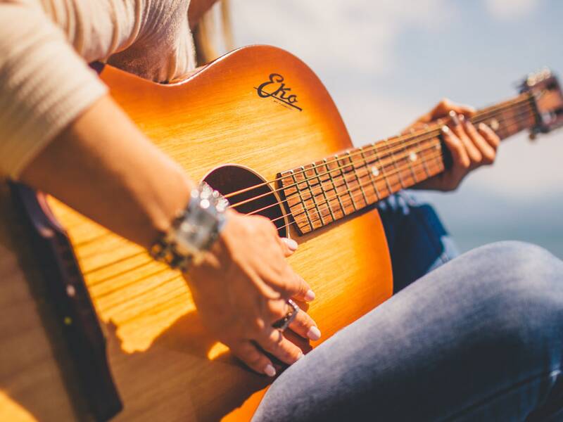 Gitarrenspielerin. Die Gitarre ist im Fokus. 