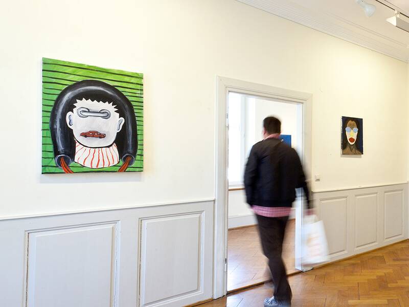 Ein Galerieraum mit verschiedenen Kunstwerken an dne Wänden.