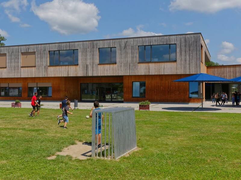 Mehrere Jugendliche spielen auf der Wiese vor dem Campusgebäude Fußball.