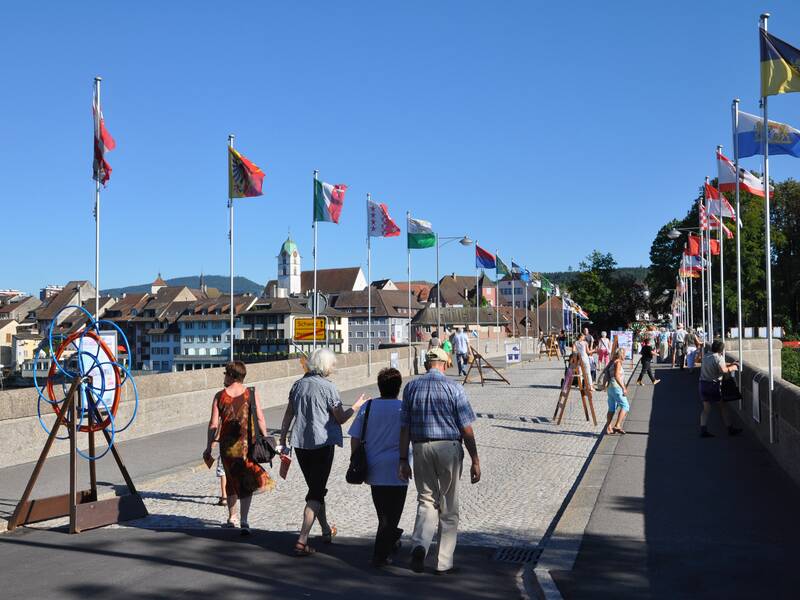 Die alte Rheinbrücke mit Fahnen und Passanten