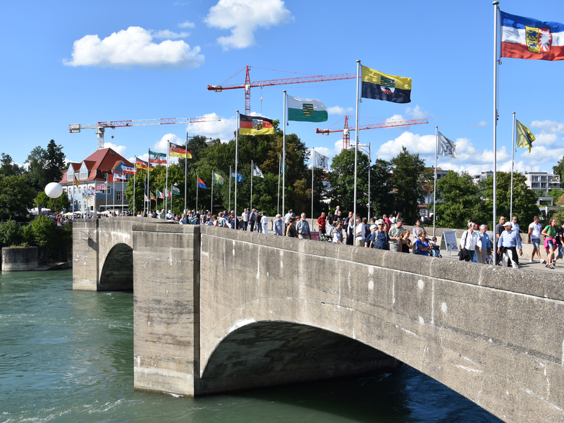 Die alte Rheinbrücke mit Fahnen und vielen Passanten
