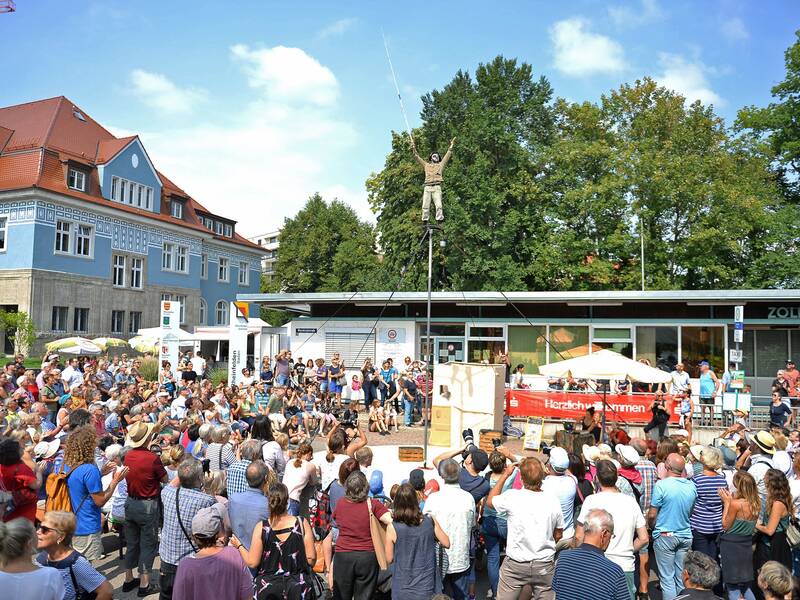 Viele Zuschauer schauen einem Akrobaten zu, der auf einer hohen Stange steht