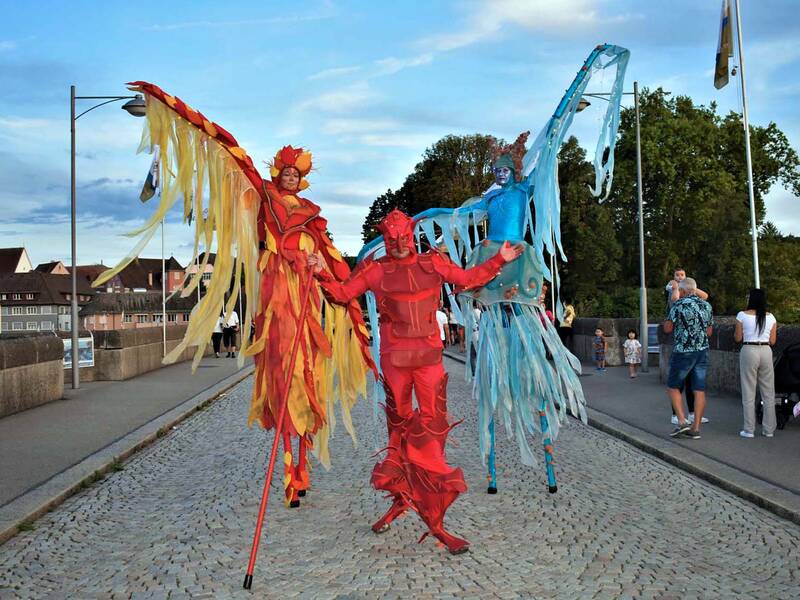 Ein Walk-Act in bunten Kostümen auf der alten Rheinbrücke