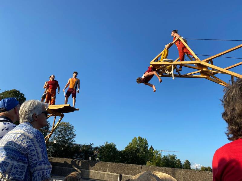 Mehrere Akrobaten stehen auf einem großen Holzgestell auf der Rheinbrücke.