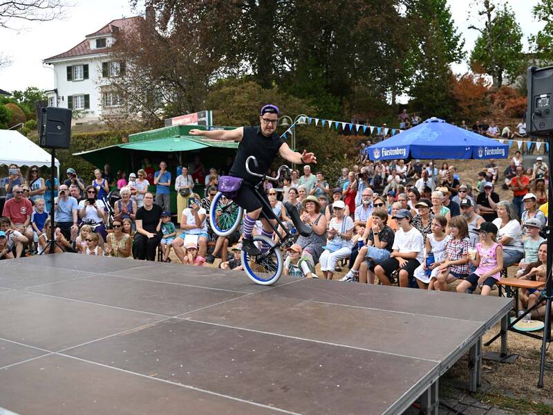 Brückensensationen 2026: Ein Künstler führt auf einer Bühne vor einem großen Publikum einen Trick mit einem Einrad vor.