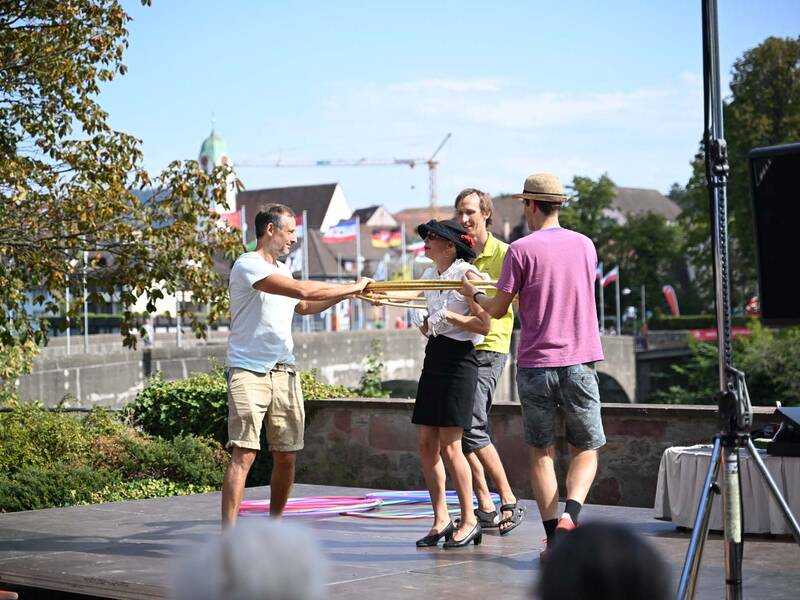Brückensensationen 2026: Vier Personen stehen auf einer Freilichtbühne und halten gemeinsam mehrere Hulla-Hoop-Reifen.