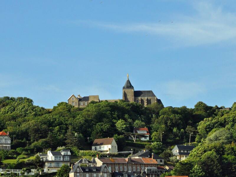 Blick in die Stadtlandschaft. Auf einem Hügel steht ein Gebäude mit einem kleinen Turm. 