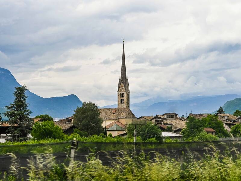 Eine malerische, von Bergen umgebene Stadt mit einer hohen Kirchturmspitze, die über den Dächern der Gebäude aufragt.