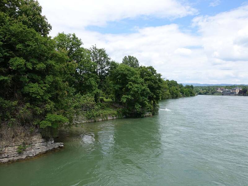 Eine Flusslandschaft mit dicht bewachsenen, grünen Ufern unter einem teilweise bewölkten Himmel.