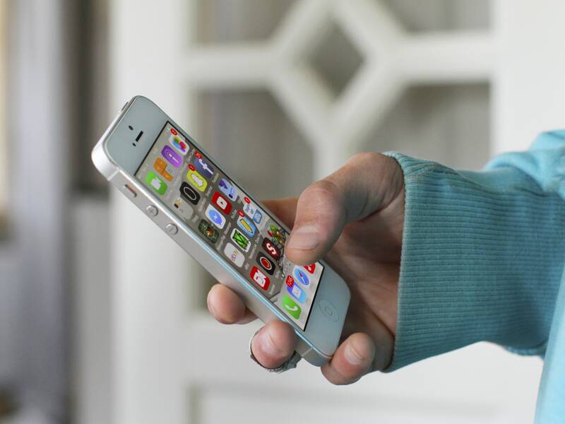 Eine Person (die nicht zu sehen ist) hält ein Smartphone in der Hand und tippt eine App an. 
