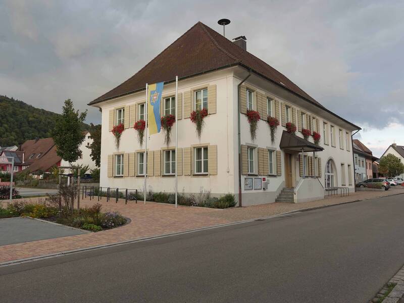 Ortsverwaltung Herten mitHertener Fahne im Vordergrund und Dorfplatz daneben