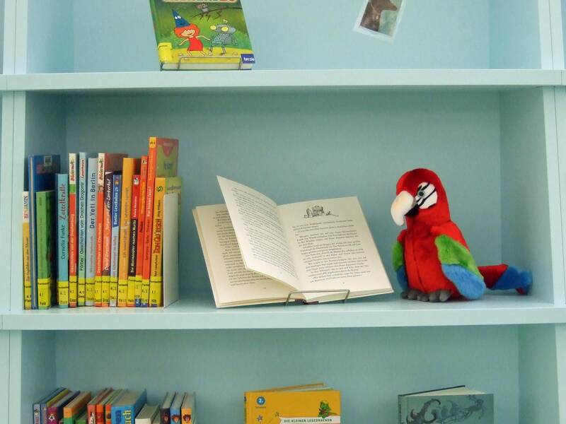 Ein Bücherregal mit Kinderbüchern und einem Plüsch-Papagei