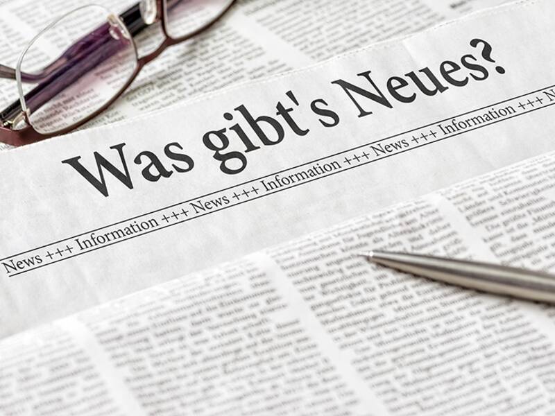 Eine Zeitung mit der Überschrfit "Was gibt´s Neues?" und eine Brille und ein Stift