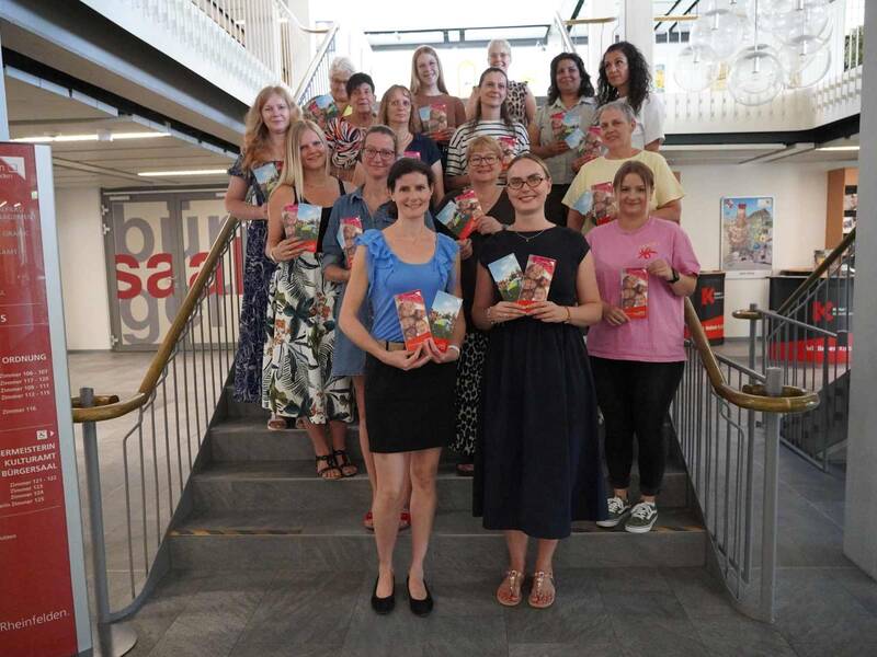 Simone Fuchs und Vanessa Hünerli von der Abteilung Schulen & Sport (1. Reihe) freuen sich gemeinsam mit den Betreuungskräften über das gemeinsam erarbeitete Leitbild für die Schulkindbetreuung.  (Gruppenbild auf der Treppe des Rathauses)