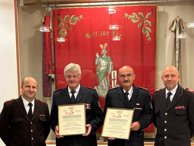 Ehrung in Neumarkt: (Vier Männer in Feuerwehruniform blicken in die Kamera): Werner Grimm (Mitte links) und Dietmar Müller (Mitte rechts) erhielten für ihr langjähriges Engagement für die Partnerschaft der Feuerwehren die „Spange für internationale Zusammenarbeit“ in Silber. Die Auszeichnung überreichten Kommandant Johannes Bertignoll (links) und sein Vorgänger sowie heutiger Präsident des Bezirksfeuerwehrverbandes Unterland, Markus Bertignoll (rechts).
