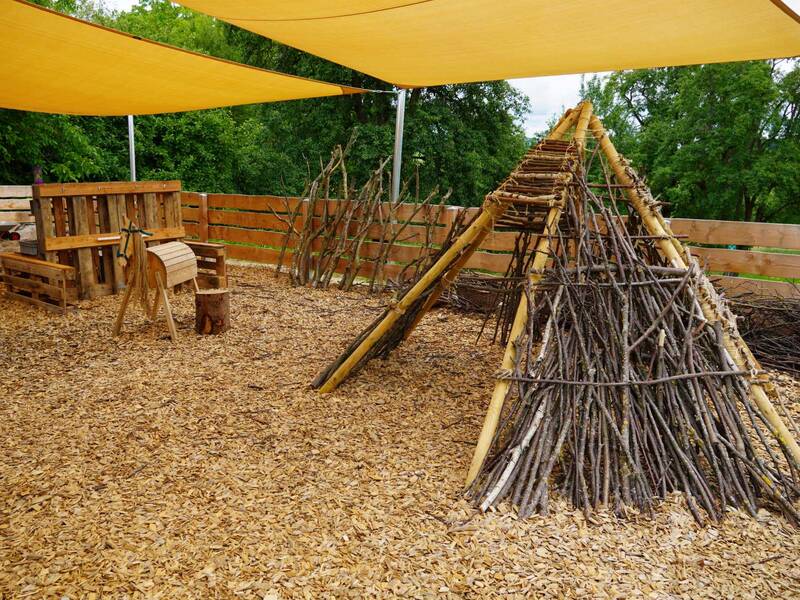 Naturkita Adelhausen: Außenbereich mit Sonnensegel und aus Holz gebasteltem Tipi.