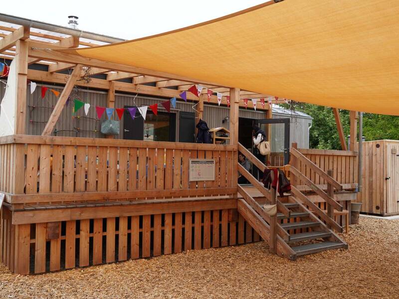 Naturkita Adelhausen: Bauwagen mit Holzterrasse und Sonnensegel.