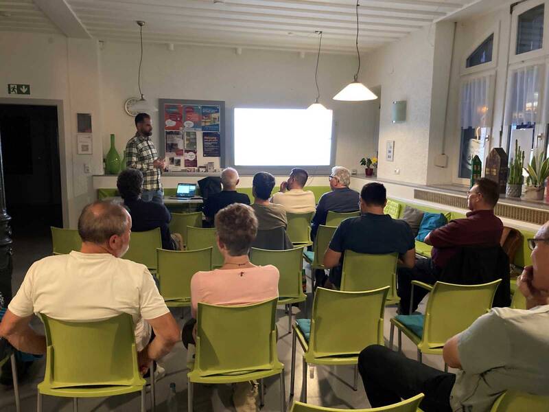Informationsabend zum Thema Heizungstausch: Zu sehen ist eine Gruppe von sitzenden Personen von hinten. Mit dem Gesicht zum Publikum steht der Energieberater der Energieagentur Südwest, und informiertüber die aktuellen Rahmenbedingungen beim Heizungstausch und die Möglichkeiten der energetischen Sanierung.